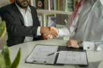 An investor shakes hands with a property manager in front of a modern building in Dubai Marina, illustrating the choice of a property management company in Dubai.