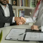 An investor shakes hands with a property manager in front of a modern building in Dubai Marina, illustrating the choice of a property management company in Dubai.