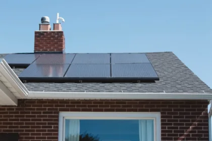 Modern climate-resilient house with solar panels on the roof and large windows, surrounded by greenery.