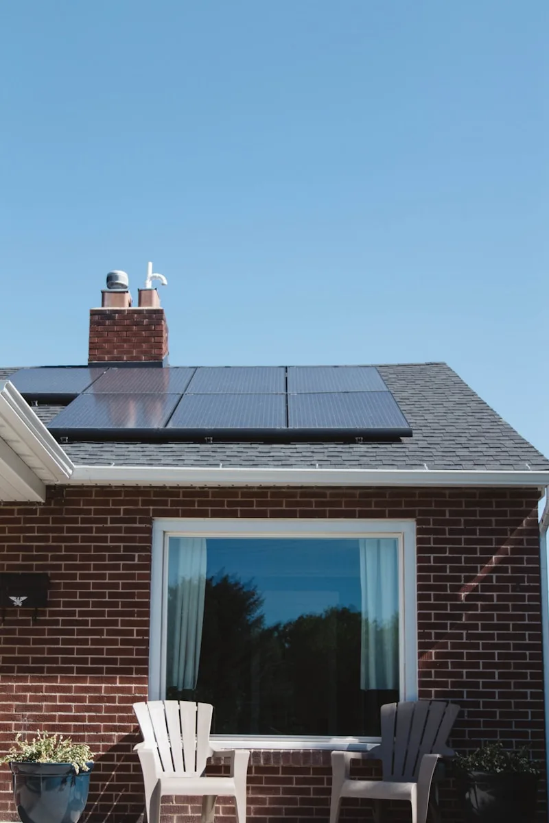 Modern climate-resilient house with solar panels on the roof and large windows, surrounded by greenery.