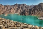 A panoramic view of the Hatta Dam, surrounded by rocky mountains under a clear blue sky.