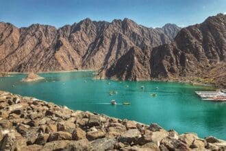 A panoramic view of the Hatta Dam, surrounded by rocky mountains under a clear blue sky.