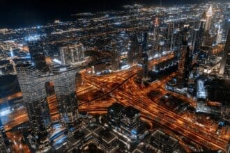 Panoramic night view of the Dubai investment neighborhoods skyline, showing illuminated skyscrapers in Downtown and Business Bay.
