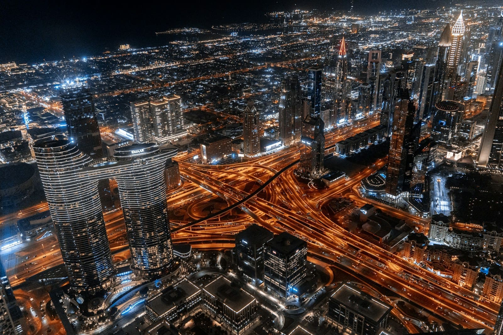 Panoramic night view of the Dubai investment neighborhoods skyline, showing illuminated skyscrapers in Downtown and Business Bay.