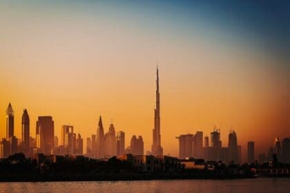 Panoramic view of Dubai skyline with construction cranes at sunset.